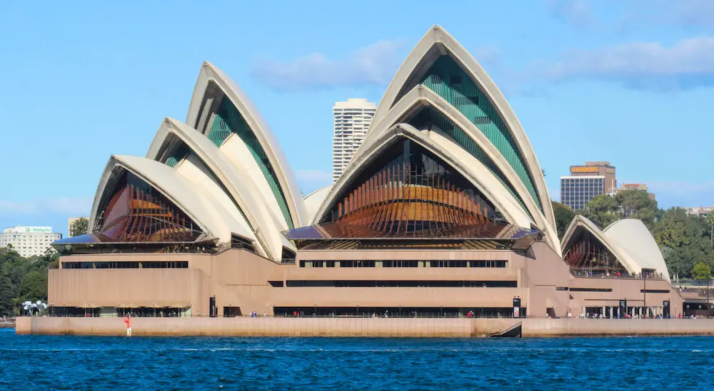 A view of the Sydney Opera House on the waterfront, featuring its distinctive white, shell-like structures.